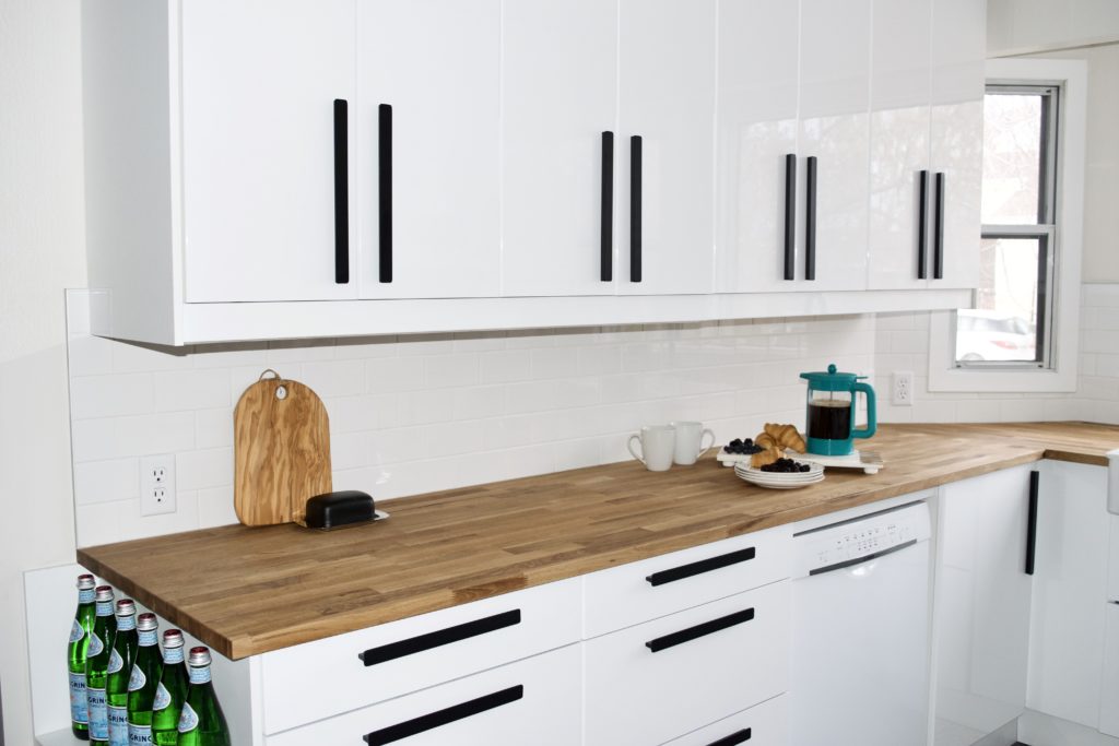 black and white modern farmhouse kitchen black handles white gloss cabinets butcher block counters white subway tile ikea hackas ringhult