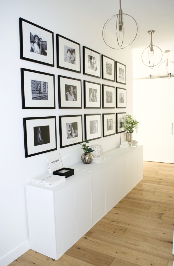 hallway entry gallery wall floor to ceiling white cabinets black frames glam scandinavian ikea oak wood floors white walls