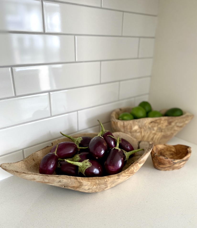 styled kitchen counter white subway tile backsplash white kitchen traditional wood bowls fruit vegetable styling decor eggplant limes
