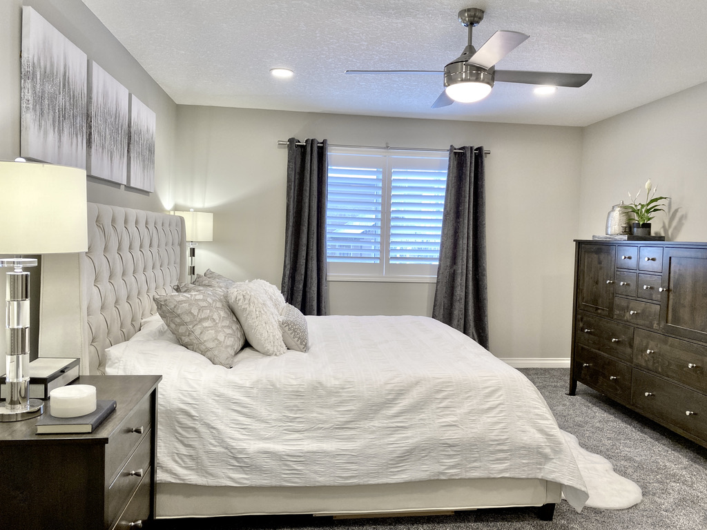 primary bedroom contemporary transitional brown wood furniture dark grey gray velvet curtains fan modern sparkle art beige bed upholstered acrylic chome table lamps bedside white ivory neutral calgary