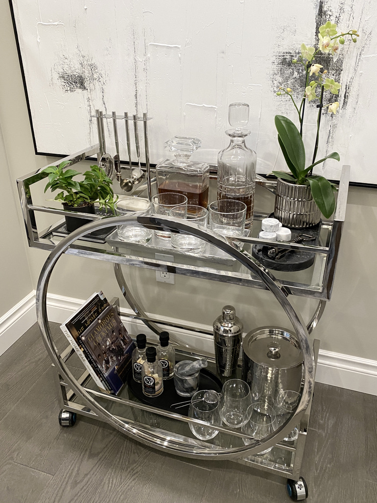 how to style a bar cart chrome wheels glasses decanter plants whiskey whisky scotch bar tools jigger books cocktails tray shaker glam mirrored