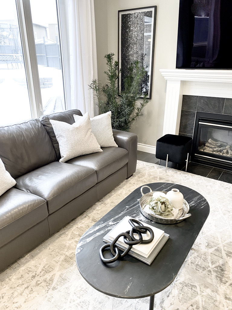 living room transitional contemporary grey leather sofas ottoman fireplace black and white gray grey velvet chain coffee table decor black marble oval tray styled styling chrome glam fireplace neutral geometric rug