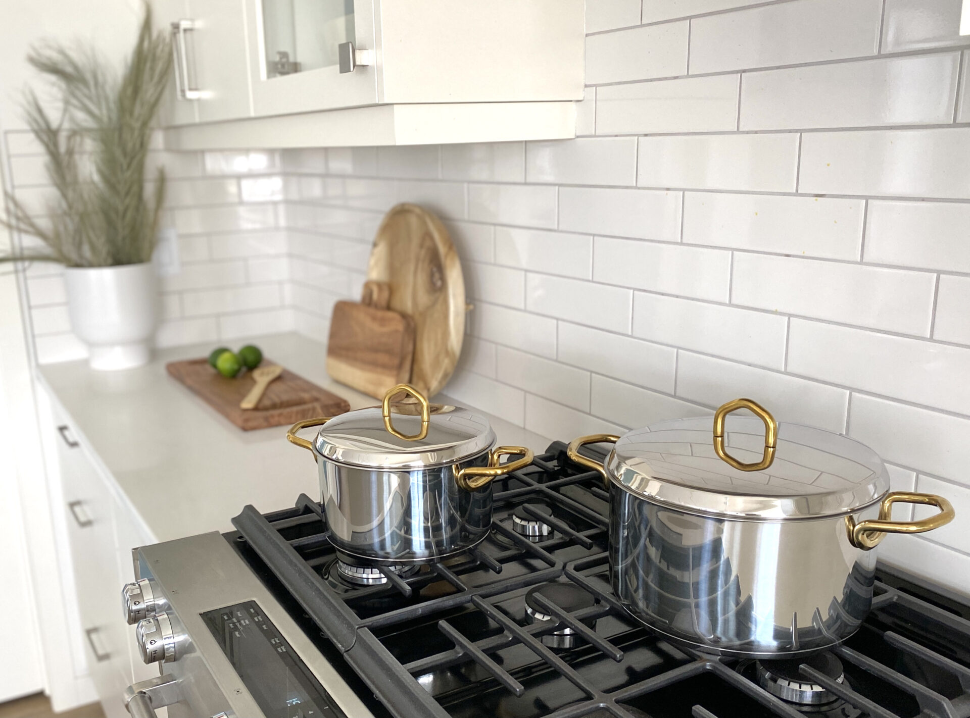 styled kitchen stove stainless steel silver gold brass pot set white subway tile backsplash white kitchen traditional