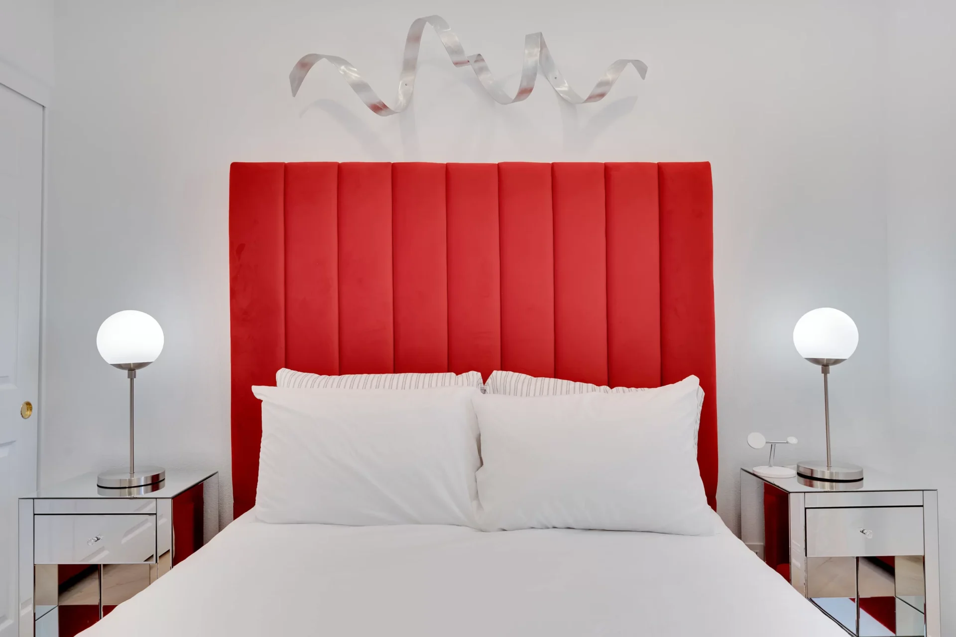 bright red bed bedroom upholstered headboard cherry primary modern silver metal wall art sculpture ribbon white clean minimal